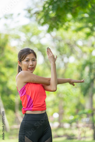 Healty Young female workout exercise before running or fitness training session in City Park. Healthy young woman warming up outdoors. She is stretching her arms at Garden park, Sports and activities