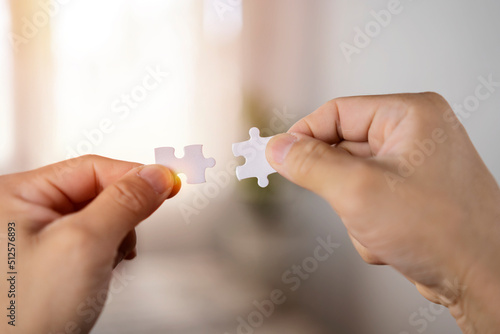 Closeup hand of woman connecting jigsaw puzzle with sunlight effect, Business solutions
