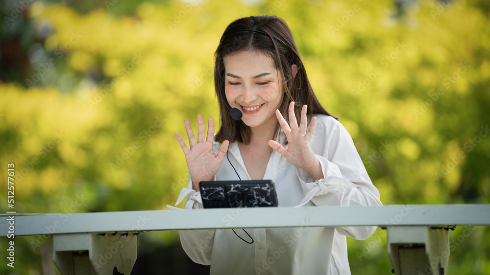 Naklejka premium Thoughtful smile Happy woman videocalling online or meeting online working with a laptop in a park