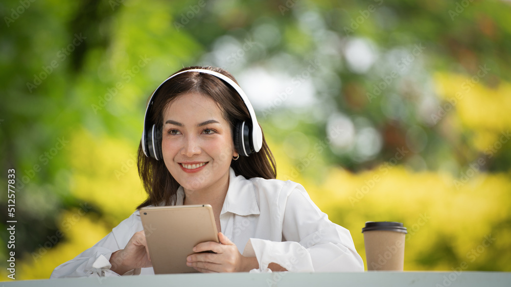 Beautiful young woman girl in beige shirt posing in Green city Park background , Smile girl Listening Music with Headphones feeling Touching Happiness. People lifestyle concept. Mock up copy space