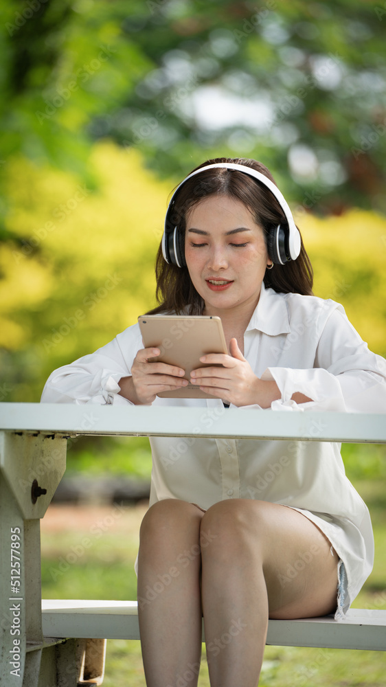 Beautiful young woman girl in beige shirt posing in Green city Park background , Smile girl Listening Music with Headphones feeling Touching Happiness. People lifestyle concept. Mock up copy space Beautiful young woman girl in beige shirt posing in Green city Park background , Smile girl Listening Music with Headphones feeling Touching Happiness. People lifestyle concept. Mock up copy space
