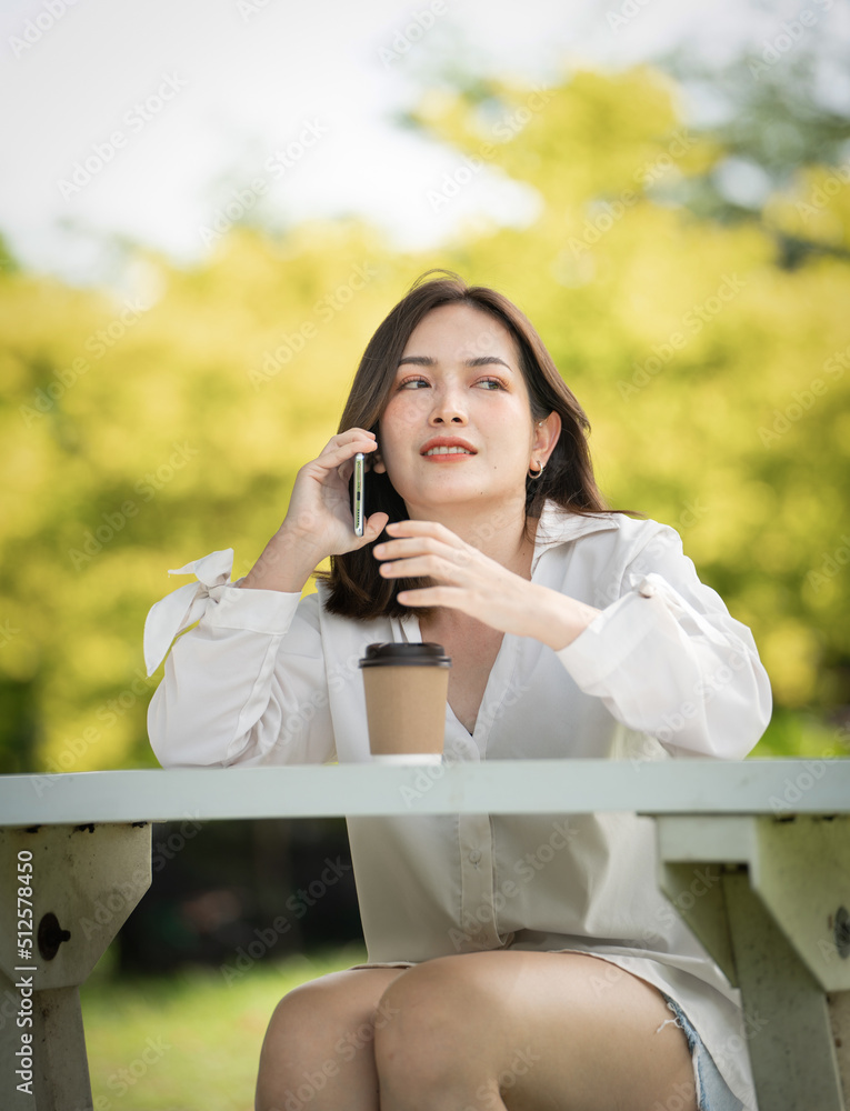 Thoughtful smile woman in park using smart phone, Portrait of a young charming business woman checking online Business work on her smart phone outdoors in the park on soft green back ground Thoughtful smile woman in park using smart phone, Portrait of a young charming business woman checking online Business work on her smart phone outdoors in the park on soft green back ground