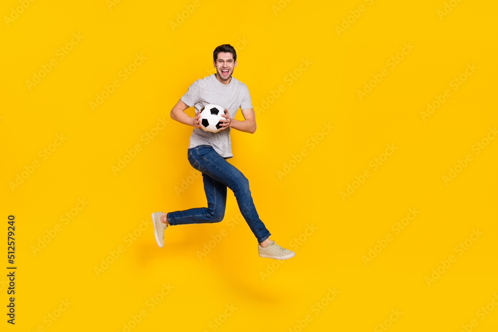 Full length body size view of attractive cheerful guy jumping playing soccer isolated over bright yellow color background