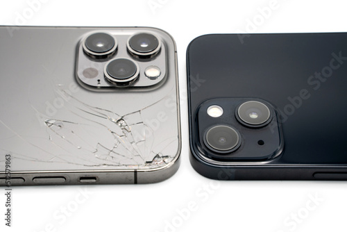 Close up of old destroyed smartphone vs. brand new isolated on white background