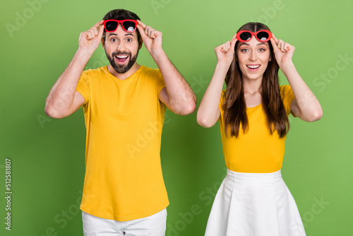 Photo of two crazy shocked people hands touch sunglass unbelievable isolated on yellow color background