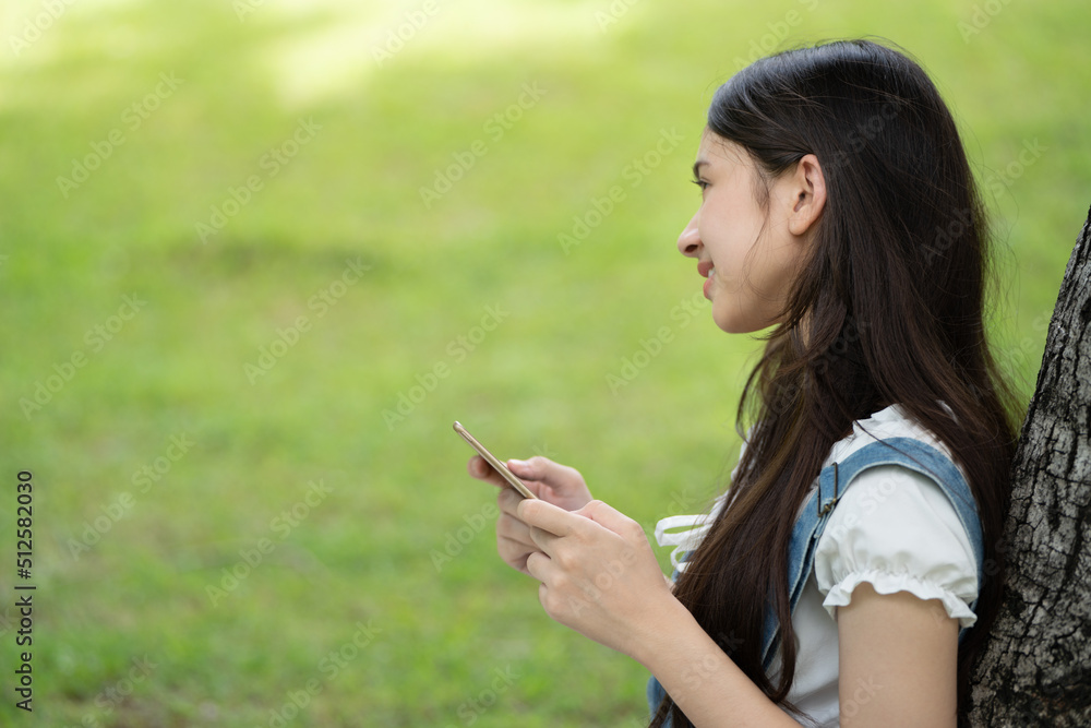 Thoughtful smile woman in park using smart phone for selfie photo , Portrait of a young charming business woman checking online Business work on her smart phone outdoors in the park on soft screen Thoughtful smile woman in park using smart phone for selfie photo , Portrait of a young charming business woman checking online Business work on her smart phone outdoors in the park on soft screen