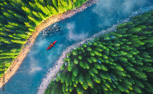 Foto Aerial view of rafting boat or canoe in mountain river and forest