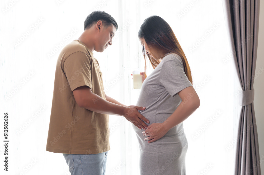Naklejka premium Young pregnant woman drinking milk at home, healthcare and pregnancy care