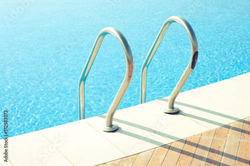 Beautiful swimming pool with shiny handrails under the bright sunlight.