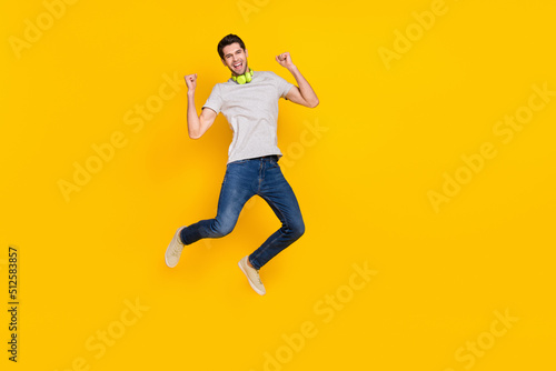 Full length body size view of attractive cheerful lucky guy jumping listening hit rejoicing isolated over bright yellow color background
