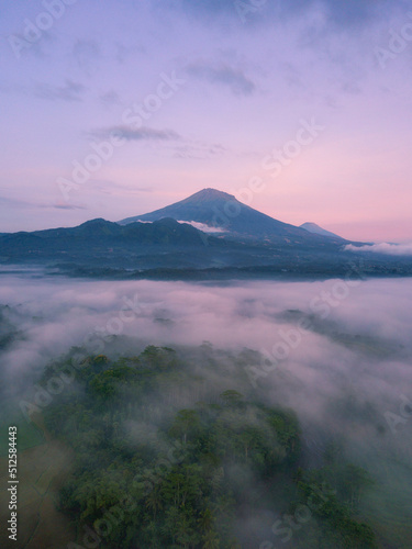 Drone photo of Mount Sumbing with sea of fog covered the land of plantation and trees in the morning. Central Java  Indonesia