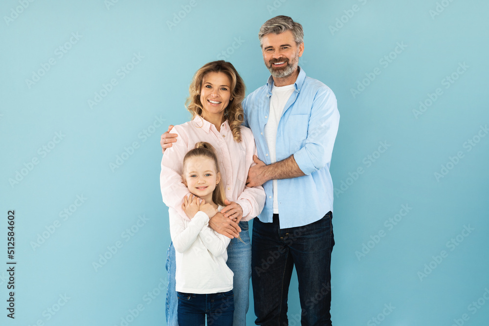 Family Of Three Embracing Smiling Standing On Blue Background Family Of Three Embracing Smiling Standing On Blue Background