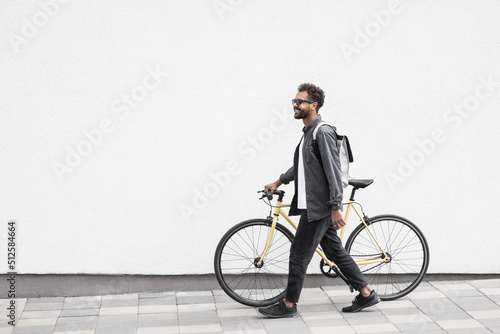 Tableau sur toile Young handsome man with bike over white wall background in city, Smiling student