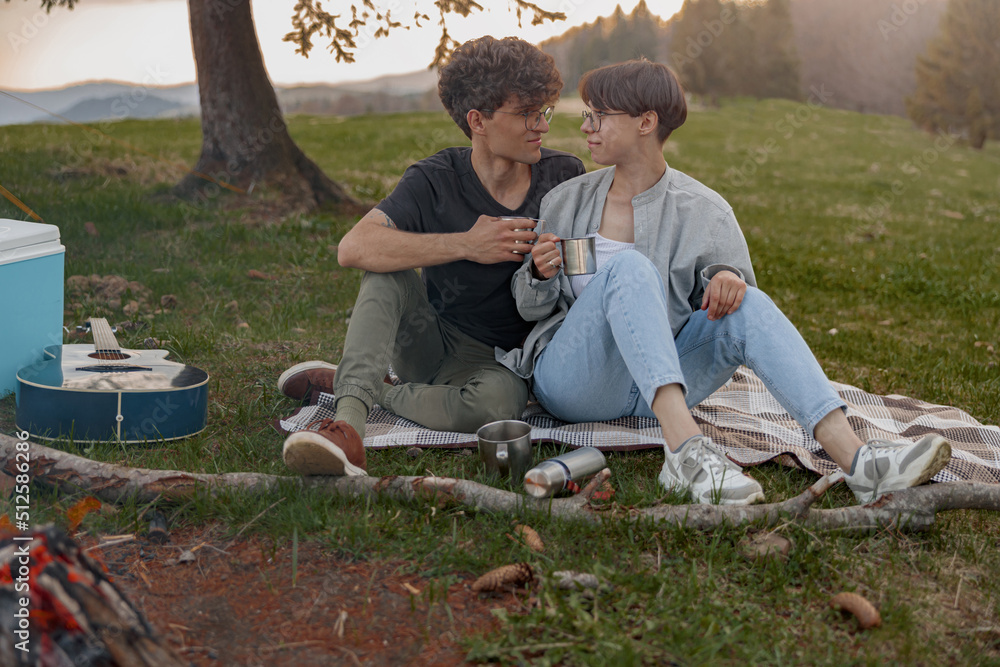 Young male and female tourists in love sitting on grass and looking at each other. Young male and female tourists in love sitting on grass and looking at each other.