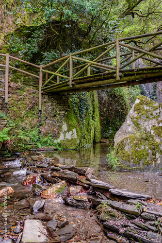 Wooden suspension bridge on hill, water and schist rocks of Barroca de Degraínhos river in Fraga de Pena, Arganil PORTUGAL photo