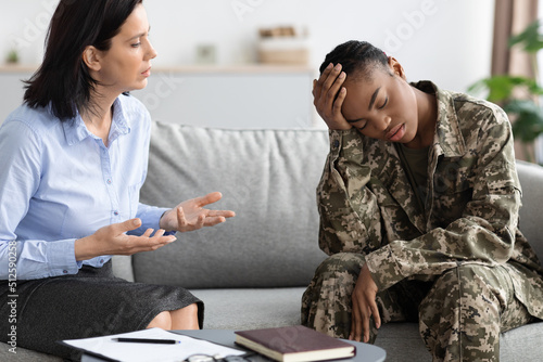 Female psychotherapist having councelling meeting with depressed black soldier woman photo
