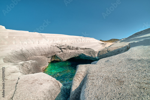 Obraz na płótnie Unique white rocks and emerald green water in sea cave, Sarakiniko beach, Milos island, Greece. Empty cliffs, summer sunshine, clear blue sky w salonie