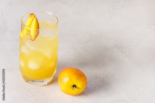 Summer Cold Drinks: Homemade Peach Lemonade with Ice Cubes in Glass on Gray Background Copy Space