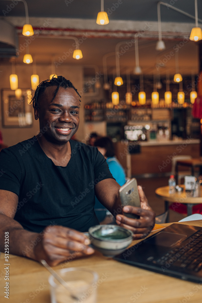 African american man using laptop while drinking coffee in a cafe African american man using laptop while drinking coffee in a cafe