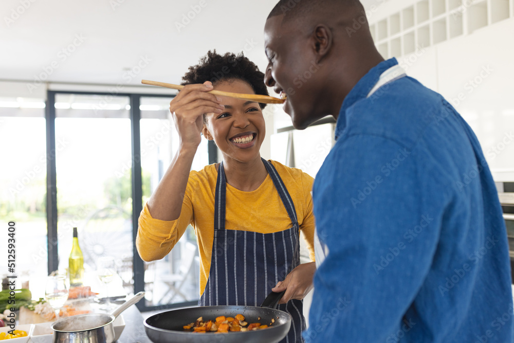 Happy african american mid adult woman giving food to boyfriend for ...