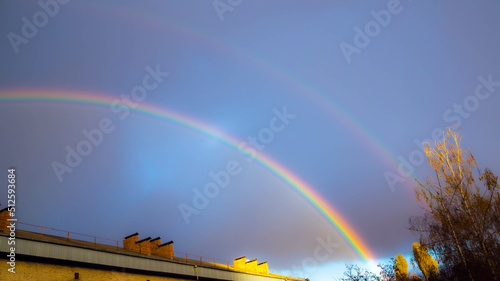 Defocused blurred purple sky sunset. Double rainbow cityscape after the rain. Dramatic nature background. Colorful rainbow against purple sky