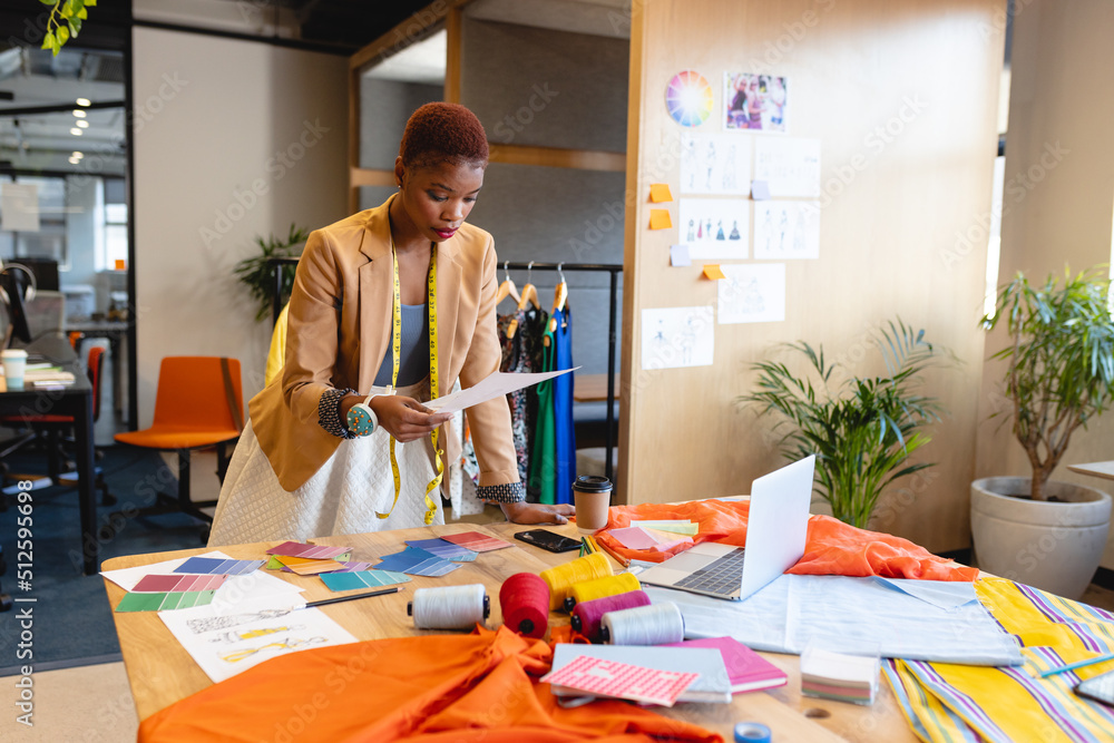 © Wavebreak Media - African american female fashion designer analyzing document at desk in studio