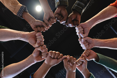 Directly below shot of multiracial fashion designers huddling with clenched fists in office