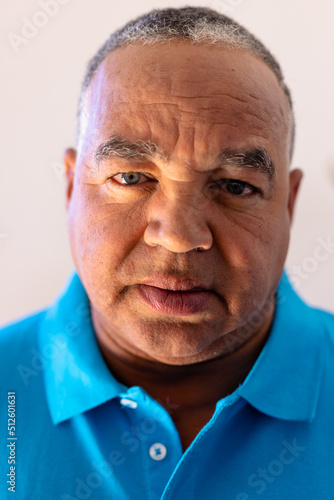 Close-up portrait of biracial senior man with gray eyes against wall in retirement home