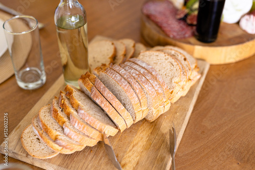 High angle view of bread slices served on board with drinking water bottle and glass on dining table