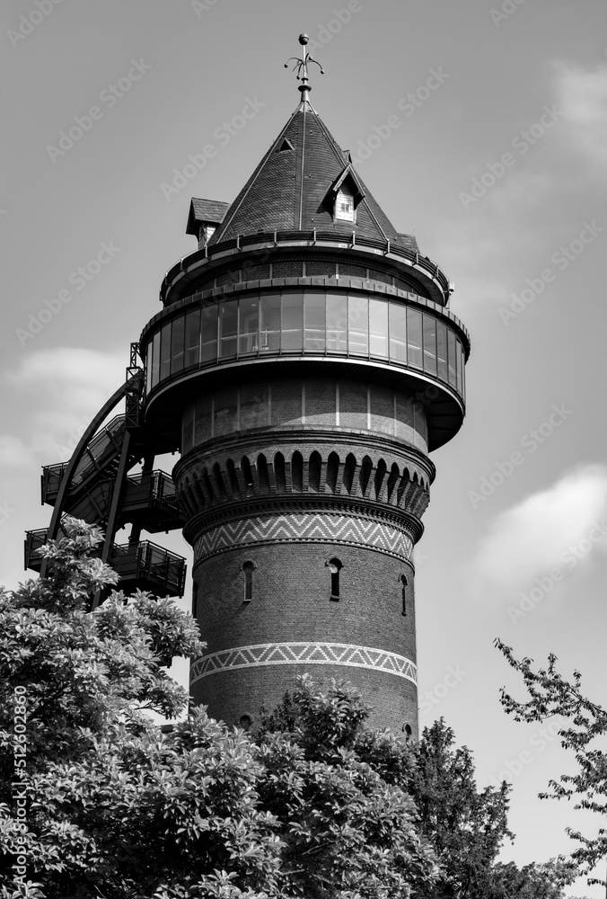 Historic water supply tower with brick facade on a sunny summer day in Mülheim. Monument, landmark and popular tourist attraction in the Ruhr Valley Germany. Black and white greyscale vintage building