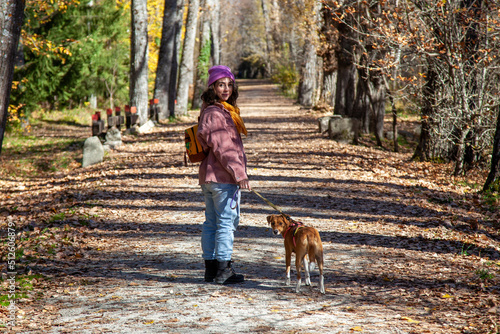 Mujer paseando por el sendero de un bosque junto a su perro. Chica de excursión con su mascota los dos mirando a cámara. photo