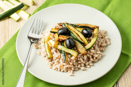pearl barley salad with zucchini on white dish whit fork