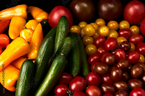 Set of delicious tomatoes, cucumbers and peppers on a black background