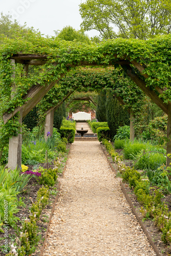 Looking down through pergola in the garden towards a water feature and seat 