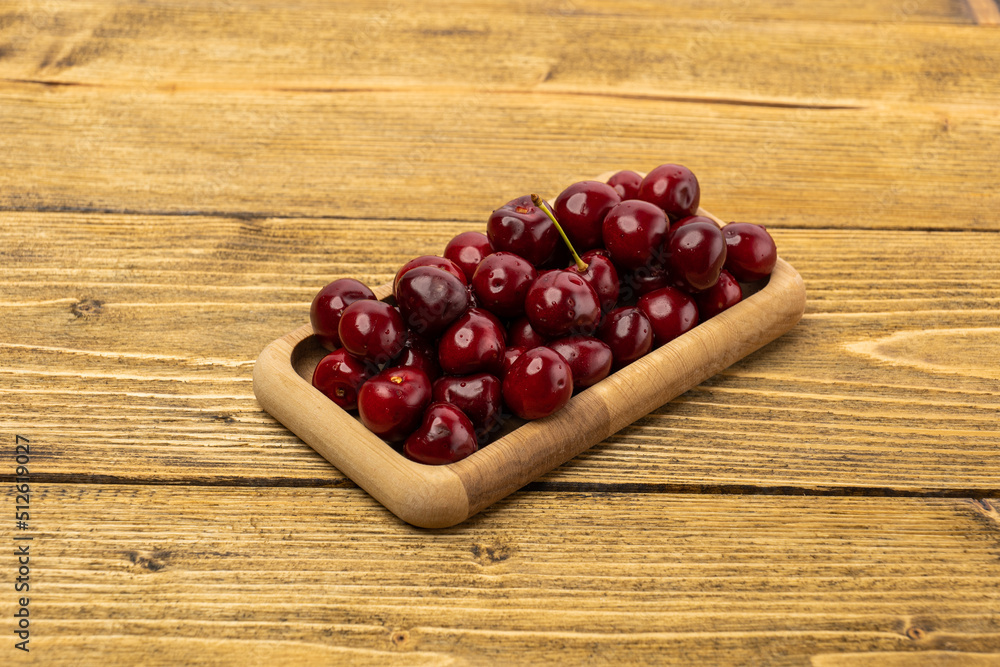 ripe red cherries in a wooden bowl on a wooden background ripe red cherries in a wooden bowl on a wooden background