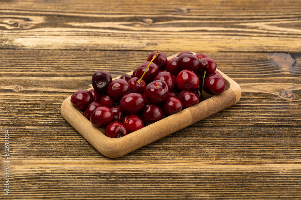 ripe red cherries in a wooden bowl on a wooden background ripe red cherries in a wooden bowl on a wooden background