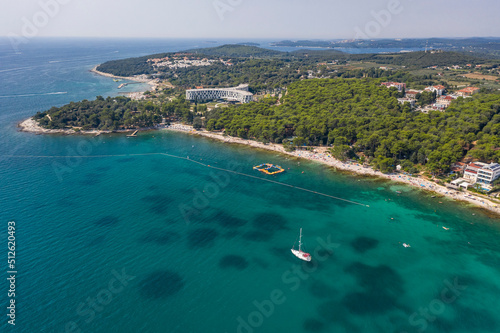 Fototapeta Naklejka Na Ścianę i Meble -  Aerial view of beach and resorts on the coast of Rovinj with green blue clear water on the Adriatic sea