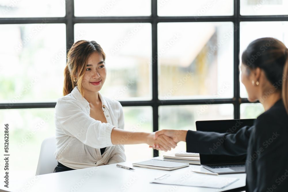 Two Businesswomen Shaking Hands In Modern Office, success business people shake hands. Two Businesswomen Shaking Hands In Modern Office, success business people shake hands.