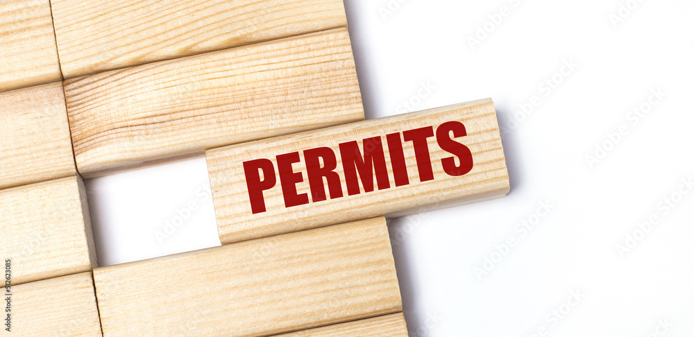 On a light background, wooden blocks with the text PERMITS. Close-up top view. On a light background, wooden blocks with the text PERMITS. Close-up top view.