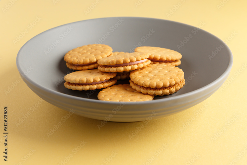 Minimalism. Cookies with fruit filling on a yellow background in a gray plate. Light background. Close-up in the center. Side view. A place to copy.