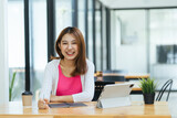 Happy casual beautiful Asian woman working on a laptop computer sitting on desk as a freelancer, work from home concept.