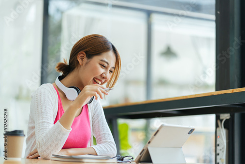 Free Download Young adult happy smiling Asian student wearing headphones talking on online chat meeting using laptop in university campus or at virtual office. College female student learning remotely. - GFXLoad