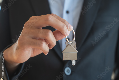 Close up view realtor broker holding home keychain in his hand.