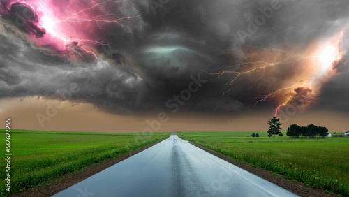 dramatic storm at sunset producing a powerful tornado twisting through the countryside with sheet lightning. Along the road and lightning. powerful lightning bolt strikes the ground in an open field © TEERAPONG