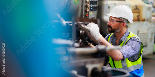 caucasian or hispanic latin man worker wearing safety goggles control lathe machine to drill components. Metal lathe industrial manufacturing factory