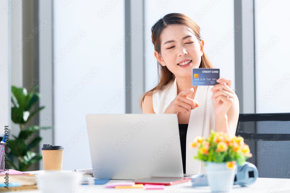 Asian businesswoman using her credit card to shop online at her company office Asian businesswoman using her credit card to shop online at her company office