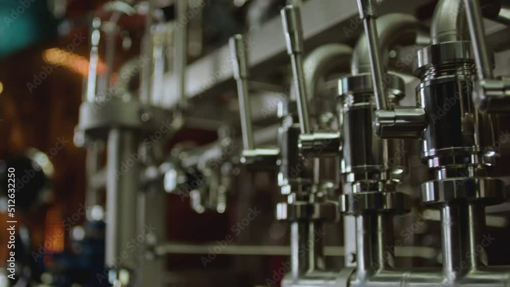 Camera moving across metallic tubes inside alcohol drinks factory. Wine , vodka cognac distilling tanks . Metal taps or kegs for pouring alcohol . slow motion close-up . Row of chrome pipes in factory Camera moving across metallic tubes inside alcohol drinks factory. Wine , vodka cognac distilling tanks . Metal taps or kegs for pouring alcohol . slow motion close-up . Row of chrome pipes in factory