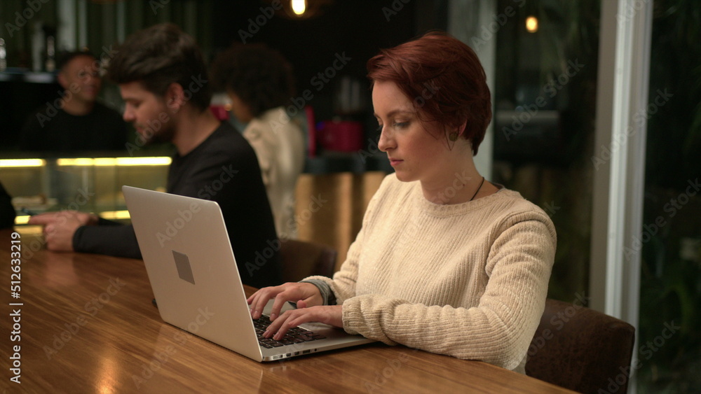 Young woman opening laptop at coffee shop working remotely. Person typing on computer at cafe Young woman opening laptop at coffee shop working remotely. Person typing on computer at cafe