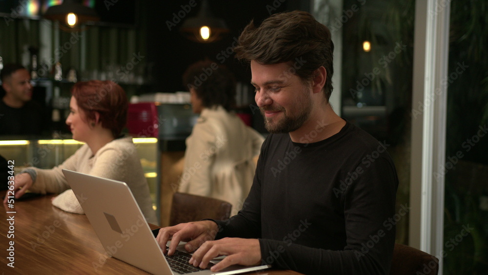 Young entrepreneur working at night in front of laptop inside cafe. Freelance worker using computer at coffee shop Young entrepreneur working at night in front of laptop inside cafe. Freelance worker using computer at coffee shop
