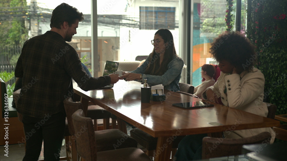 Male customer picking cups of expressos at coffee shop counter and bringing to female friend Male customer picking cups of expressos at coffee shop counter and bringing to female friend